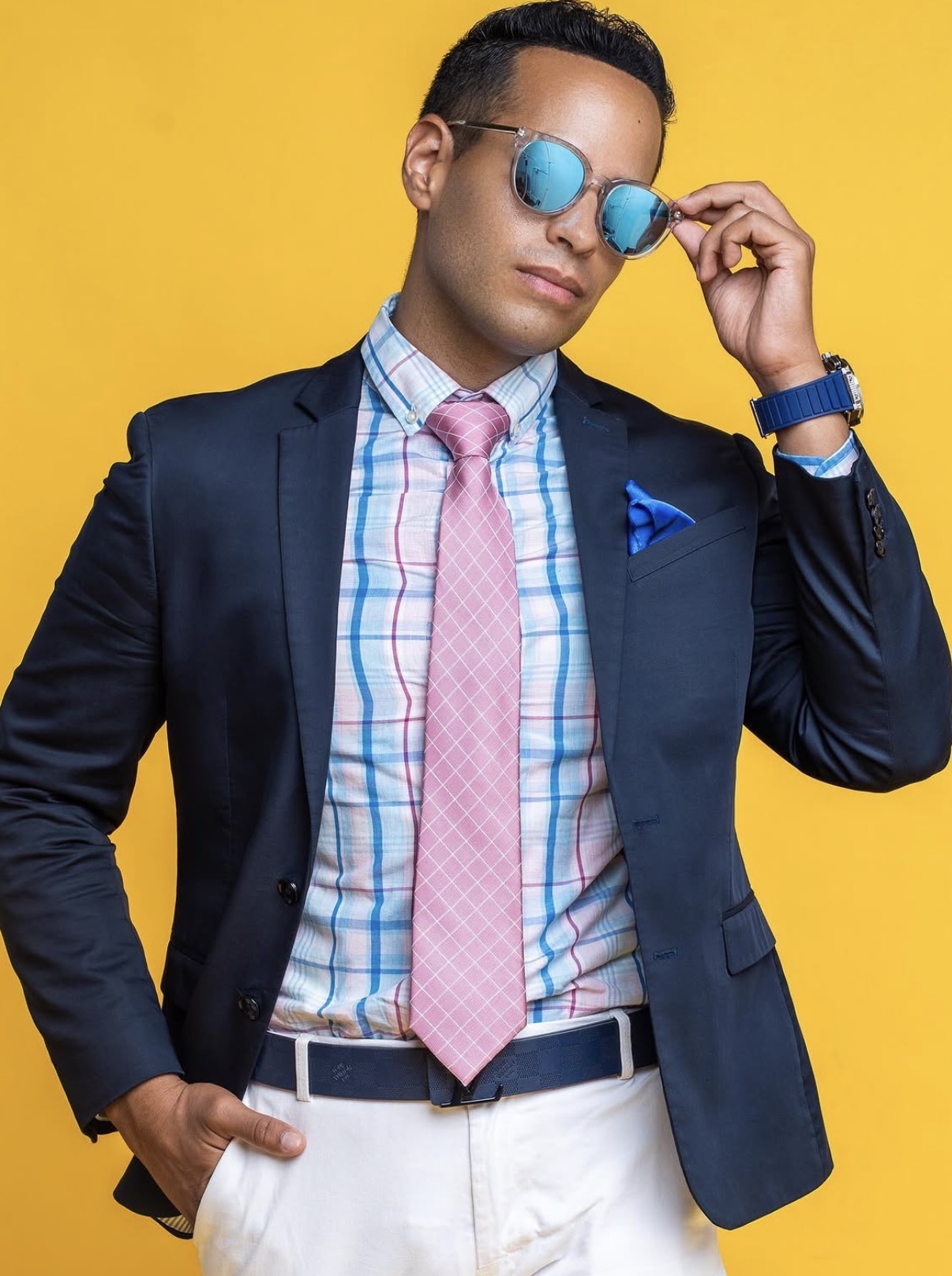 Andrew Goldstein in a navy blazer and sunglasses against a bright yellow backdrop